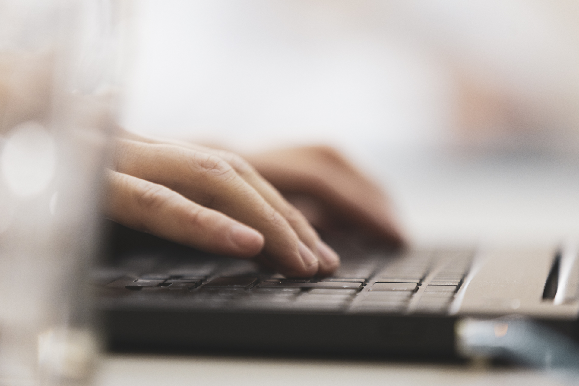 Primer plano de manos escribiendo en una notebook, como detalle de trabajo y tecnología.